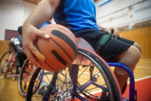 close up shot of a person sitting on wheelchair while holding a ball