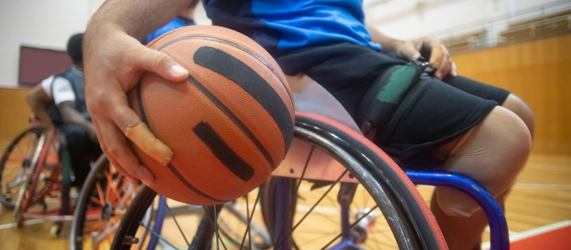 close up shot of a person sitting on wheelchair while holding a ball